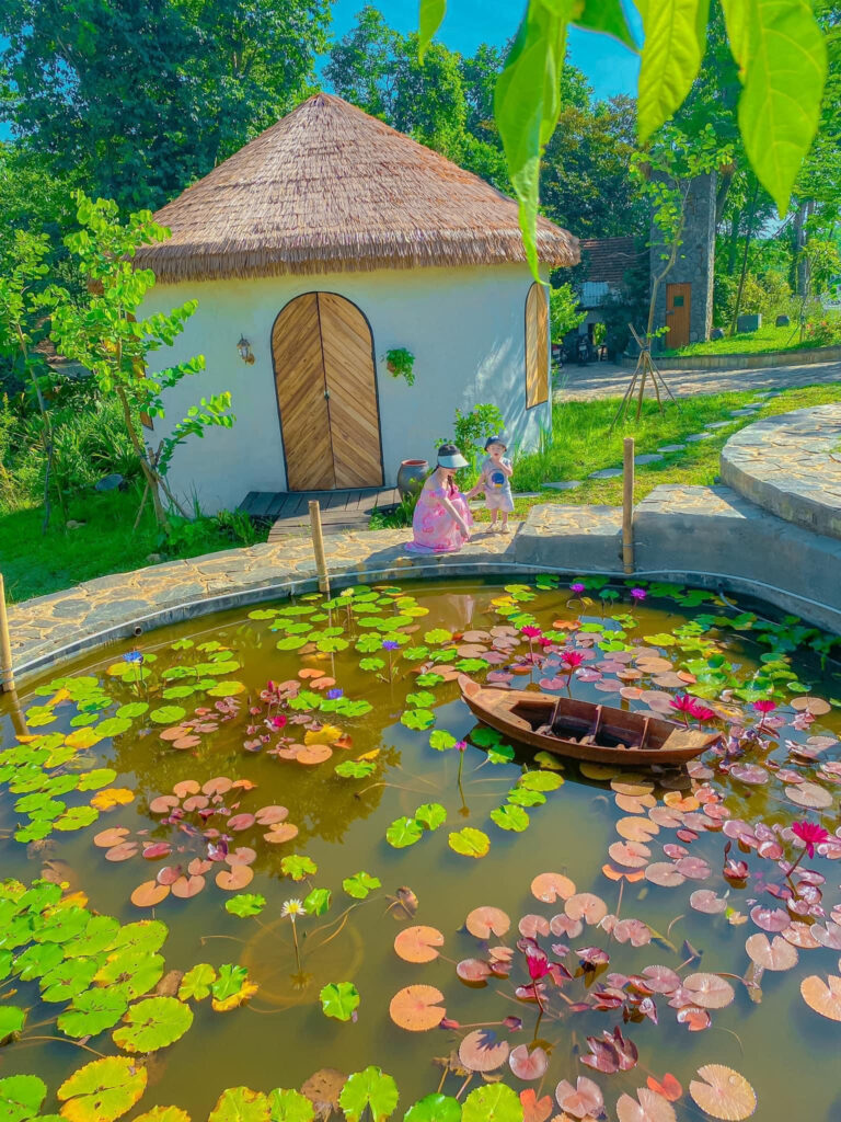Vì Sao 90% Resort Chọn Rơm Nhân Tạo Làm Mái? Dự Án V Village Đà Nẵng Là Ví Dụ Điển Hình 6 Ngôi nhà mái lá sử dụng rơm nhân tạo làm mái, nằm cạnh hồ sen và bao quanh bởi cây xanh.