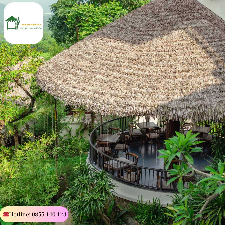 Bungalow mái rơm nhân tạo nằm giữa không gian cây cối xanh tươi.