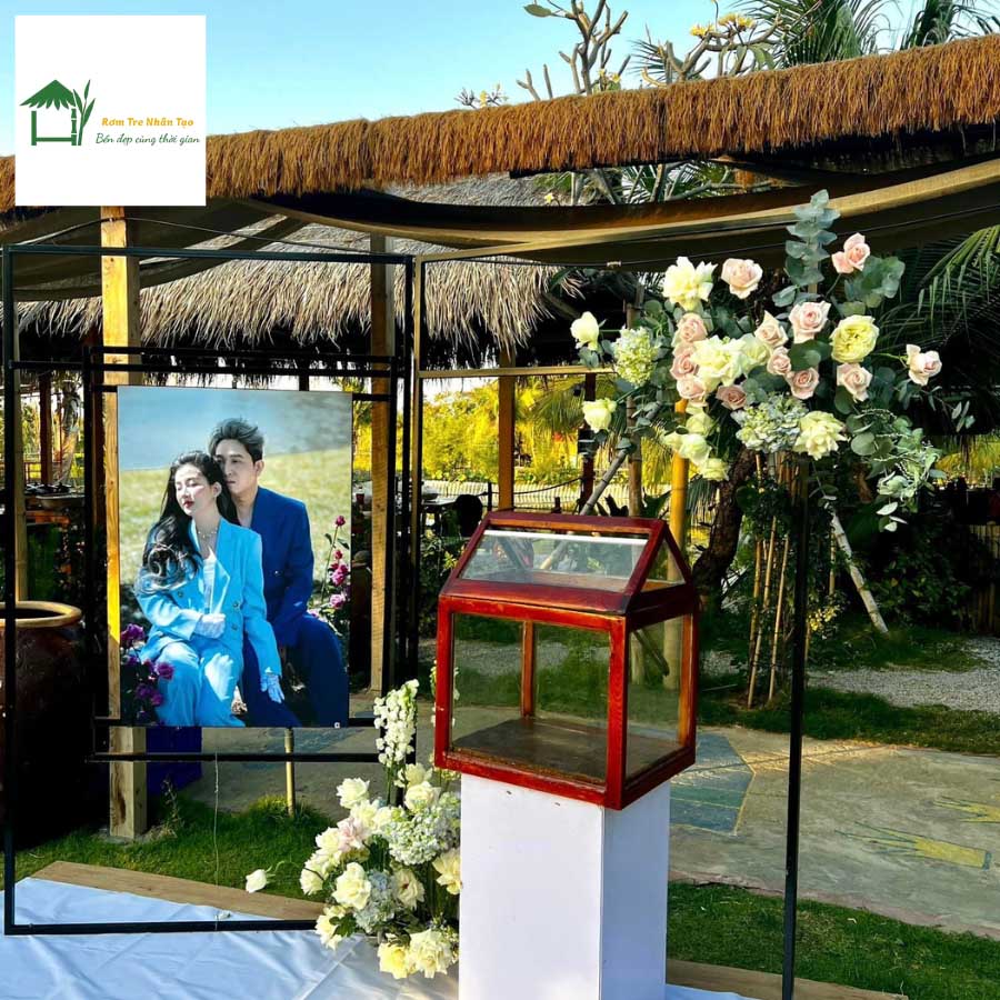 Không gian sân khấu ngoài trời trang trí mái bằng thảm rơm nhân tạo kết hợp hoa tươi.
