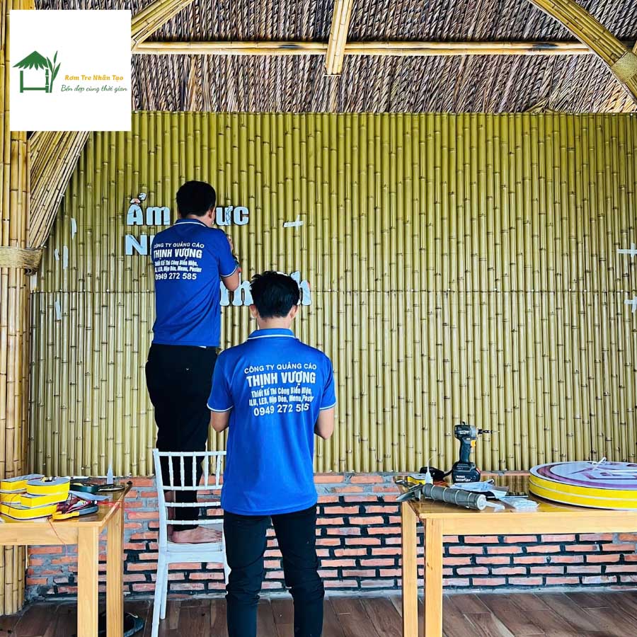 Nhân viên đang thi công lắp đặt vách tre nhân tạo trong quán cafe, nền gạch cổ, mái lá.