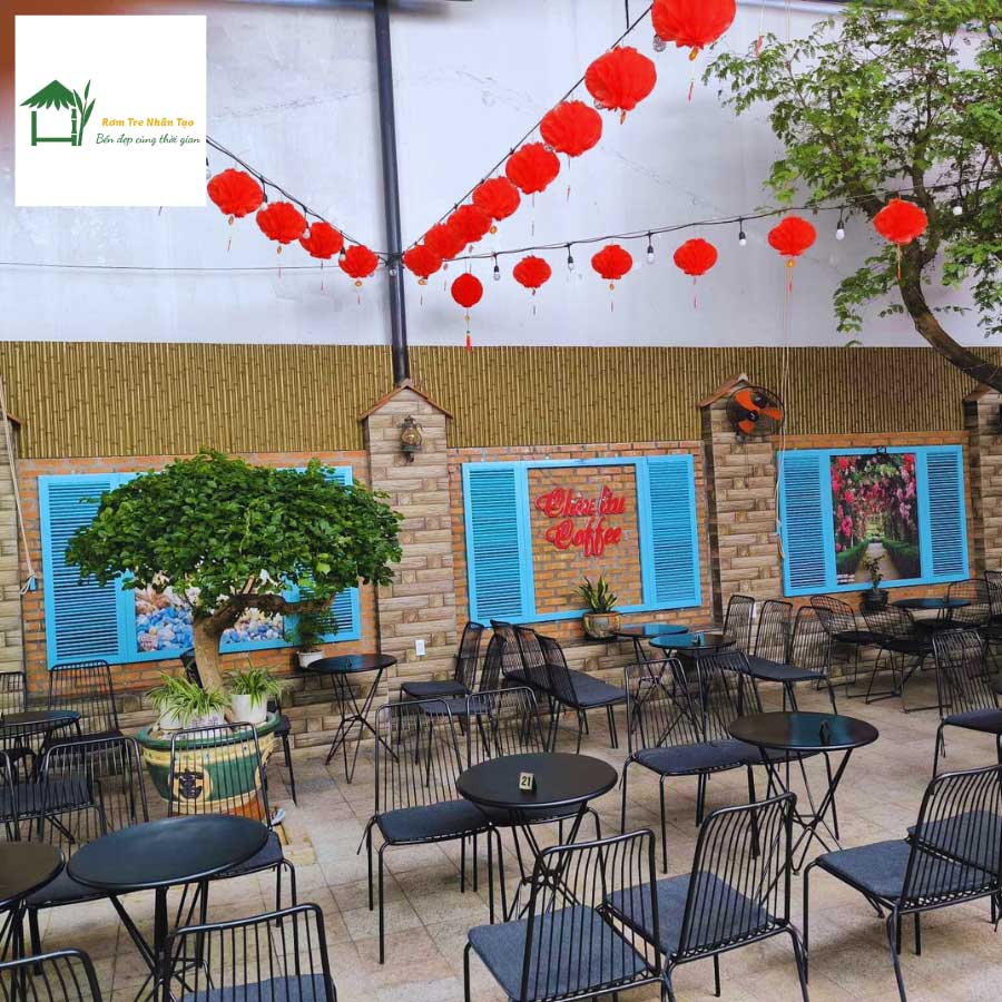 Khu vực bàn ghế ngoài trời quán cafe, trang trí vách tre nhân tạo, đèn lồng đỏ treo trang trí Tết.