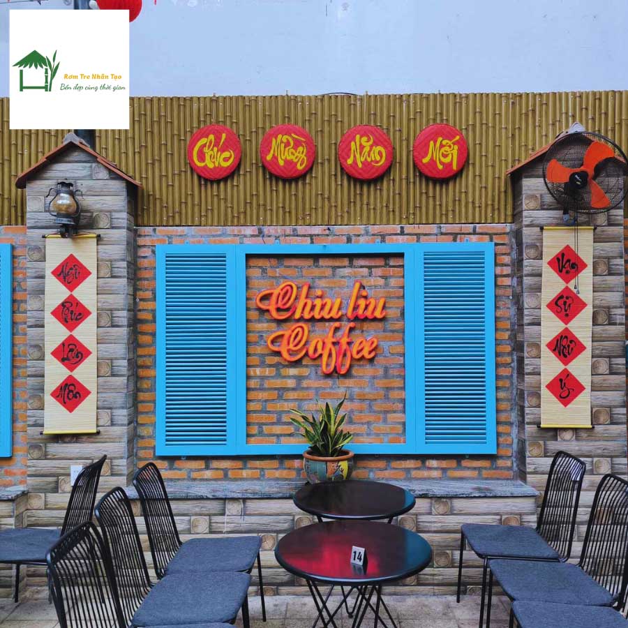 Quán cafe trang trí vách tre nhân tạo, cửa chớp xanh, bàn ghế kiểu cổ điển, đèn lồng đỏ treo phía trên.