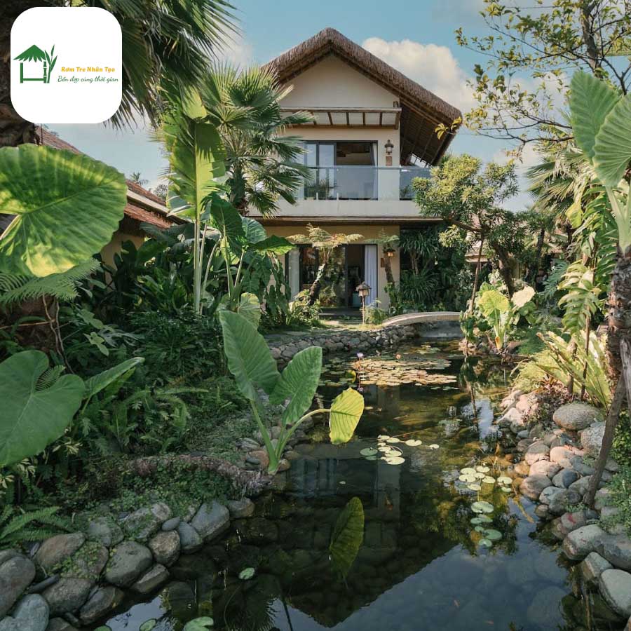 Lối đi dẫn vào resort với cây xanh và hồ cá.